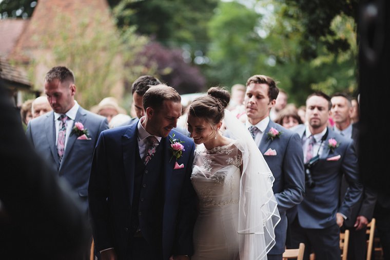 Bride and Groom laughing together during their wedding service at Ratsbury Barn