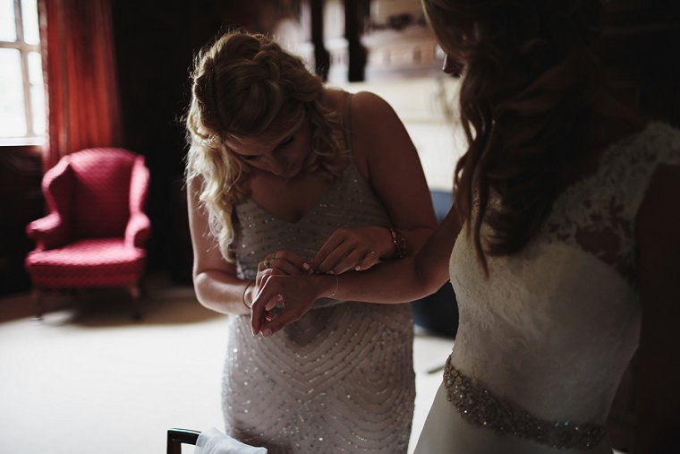 bridesmaid helping bride with her bracelet