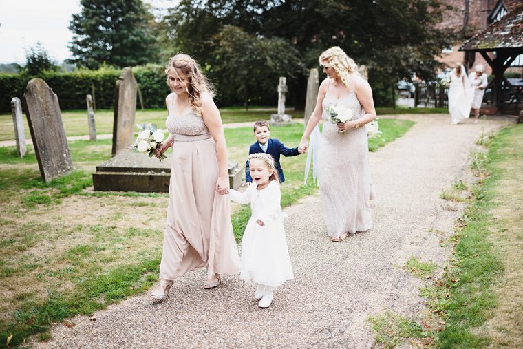 Bridesmaid holding flower girls hand