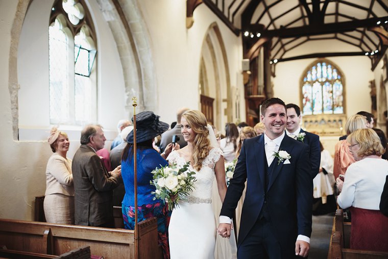 Bride and Groom holding hands as they walk down the aisle