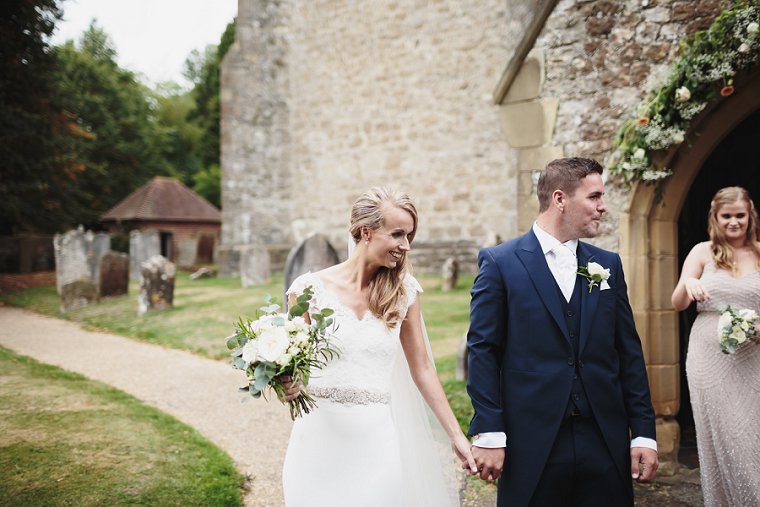 Bride and groom smiling and holding hands outside church