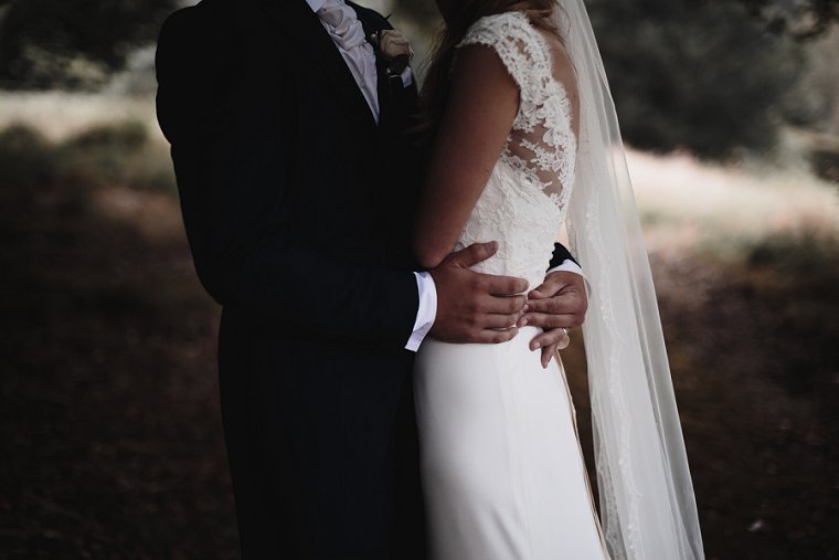 Close up photo of grooms hand on brides waist