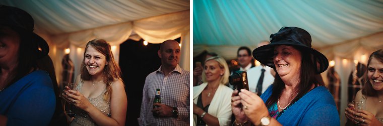 Guests laughing and taking pictures as Bride and Groom cut the cake