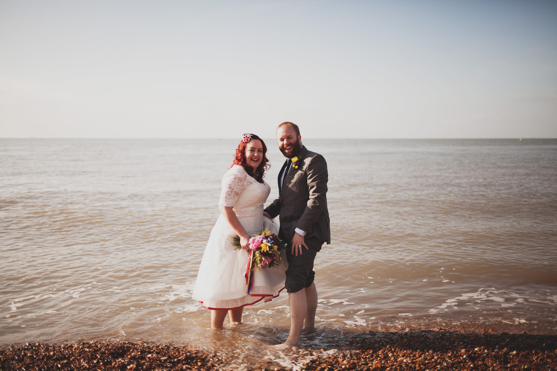 Bride and Groom paddlin in sea at Whitstable