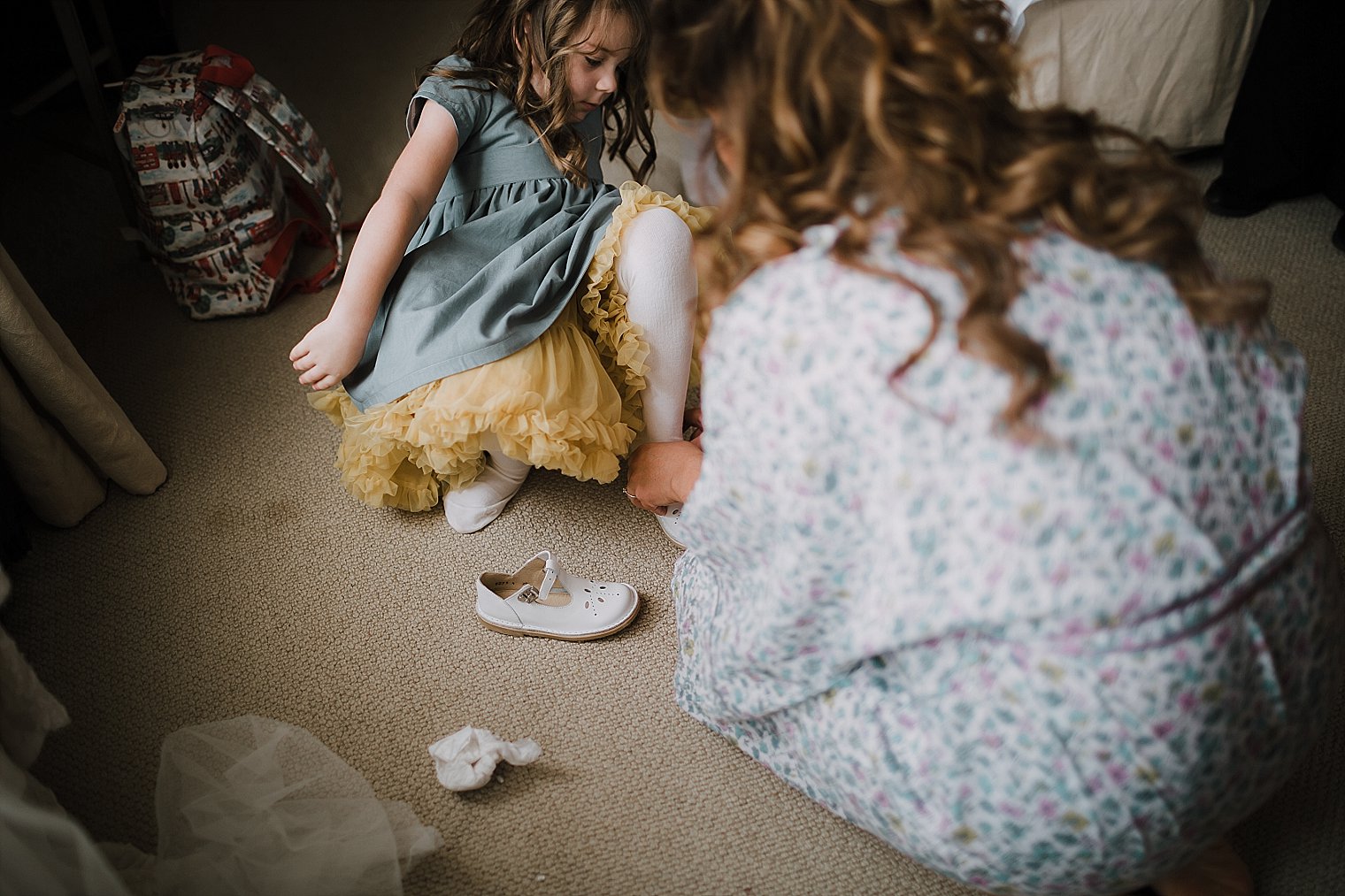 Bride helping her flowergirl put her shoes on