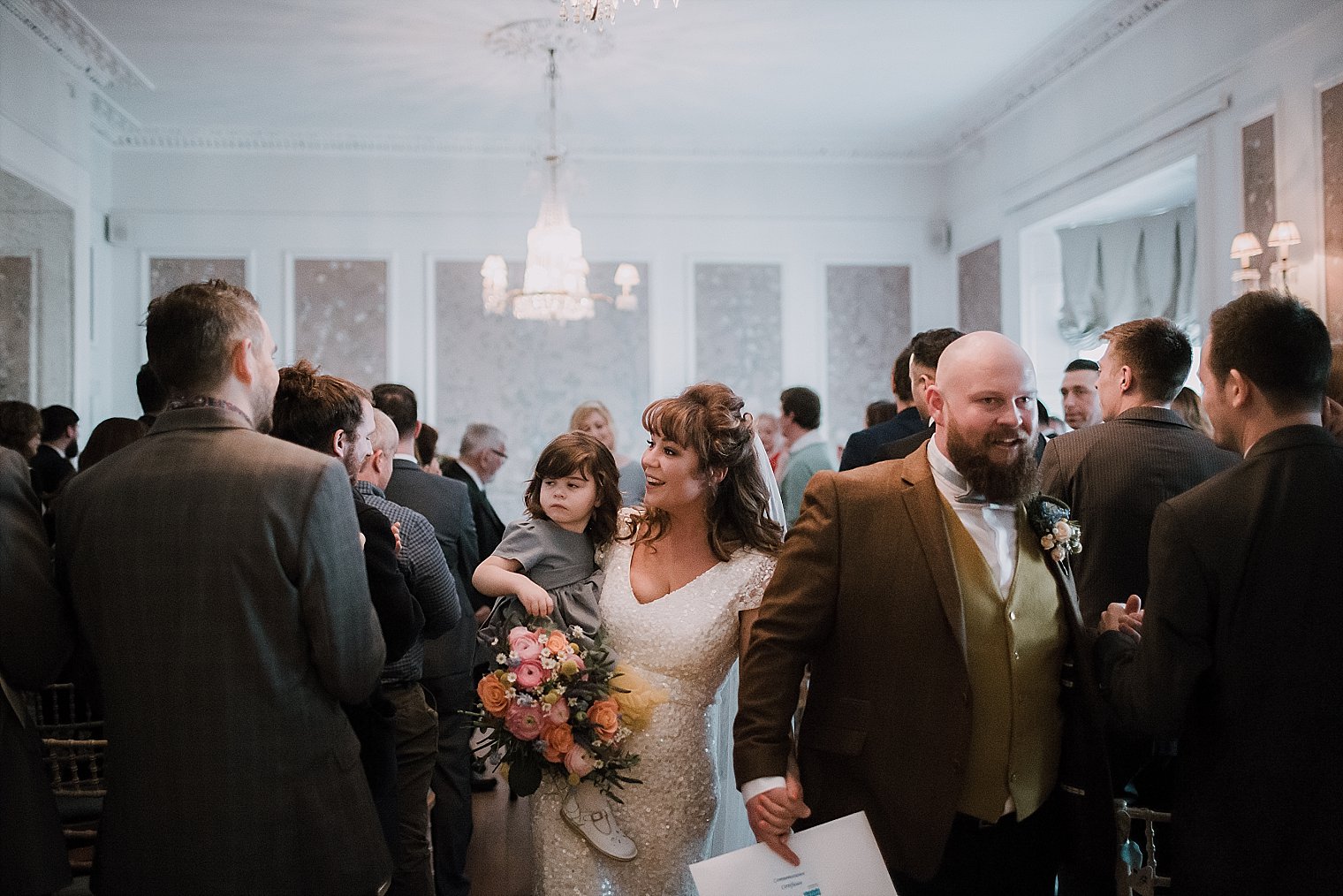 Bride groom and their daughter walking back down the aisle