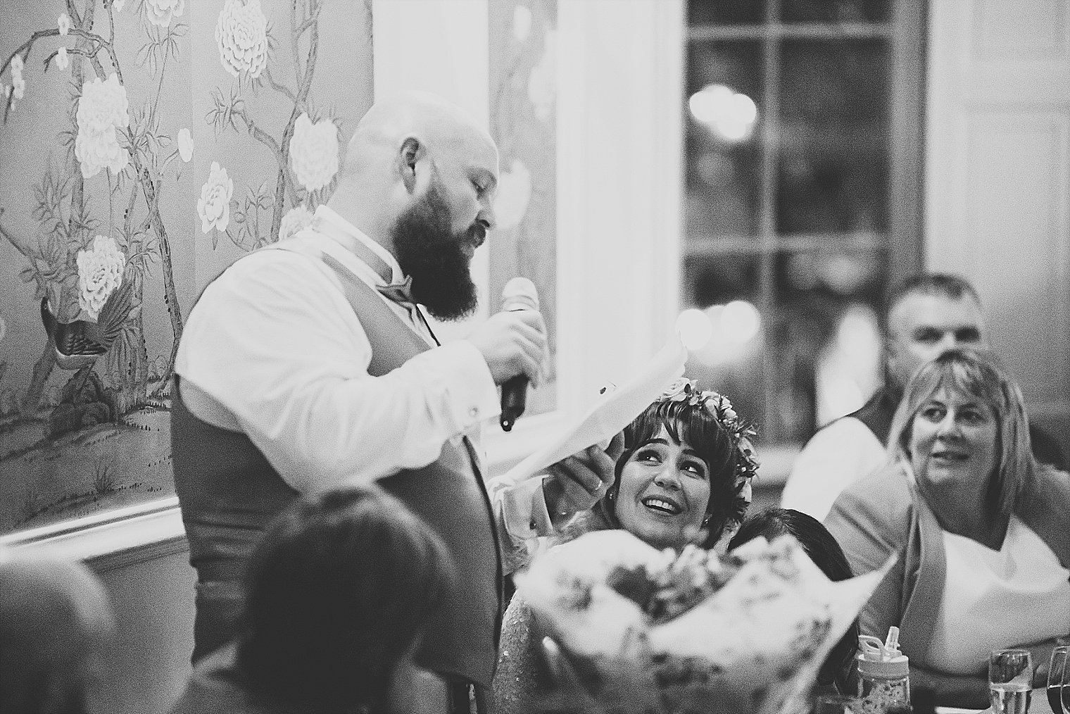 Bride looking at groom and smiling during his speech