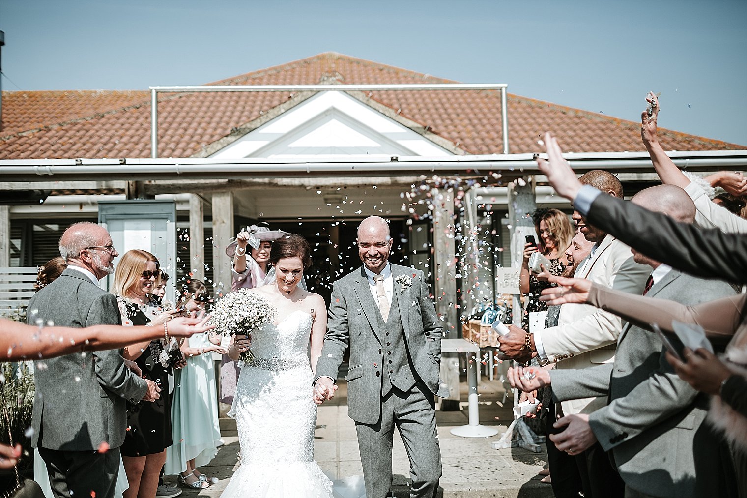 Bride and Groom having confetti thrown on them outside The Gallivant in Camber