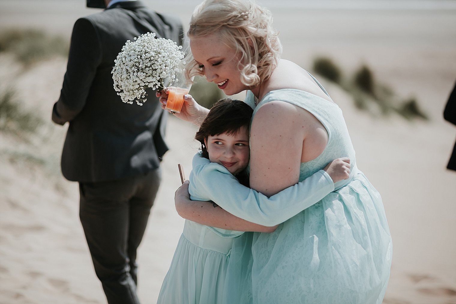 Bridesmaid and flower girl hugging