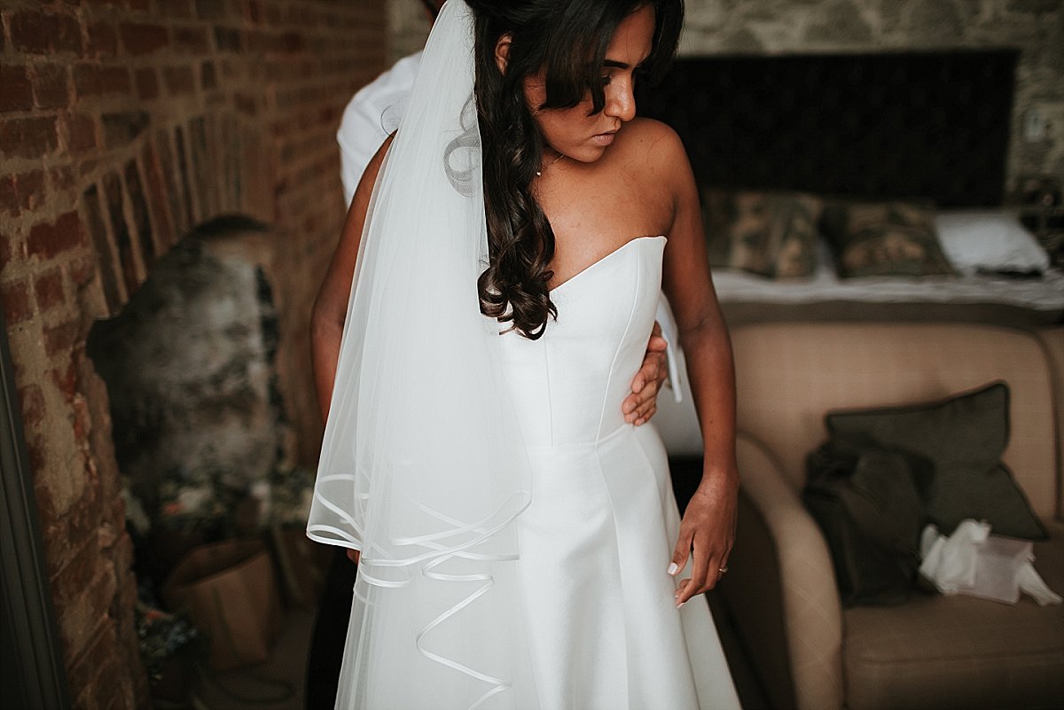 Bride putting wedding dress on