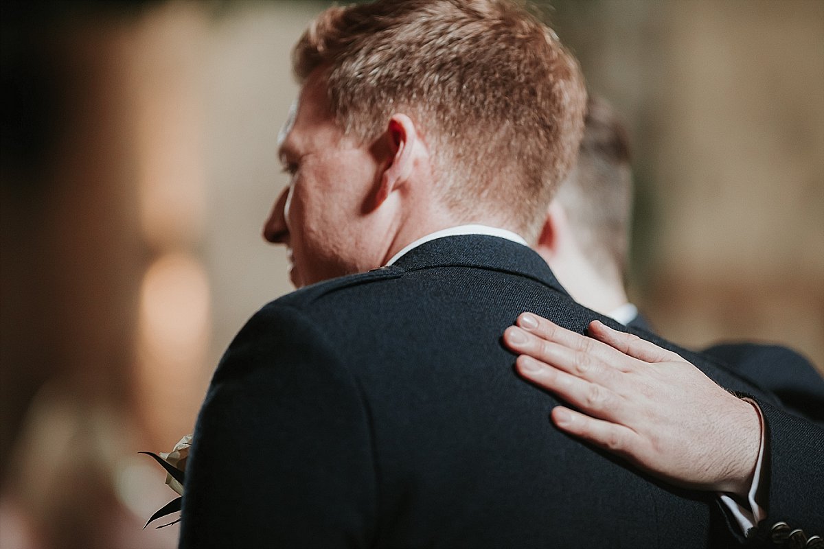 Grooms hand on shoulder of his best man