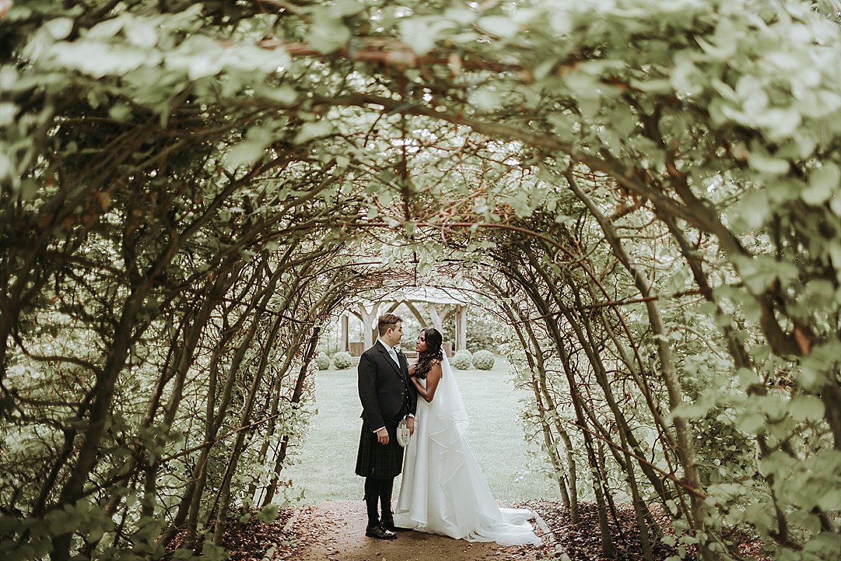 Bride and groom posing in archway for wedding photography at Cripps Barn