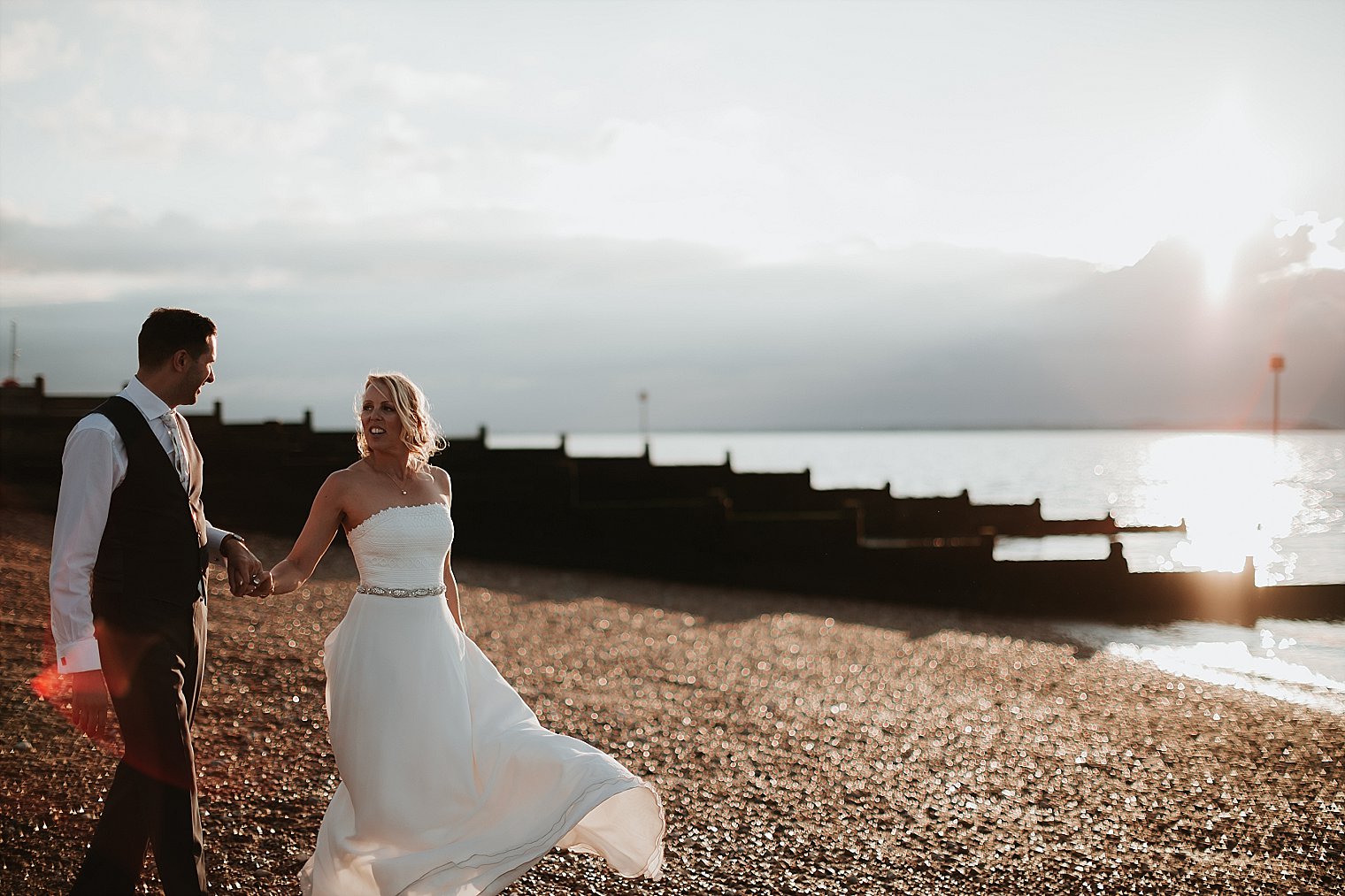 Bride and Groom walking on pebbles at Whitstable beach