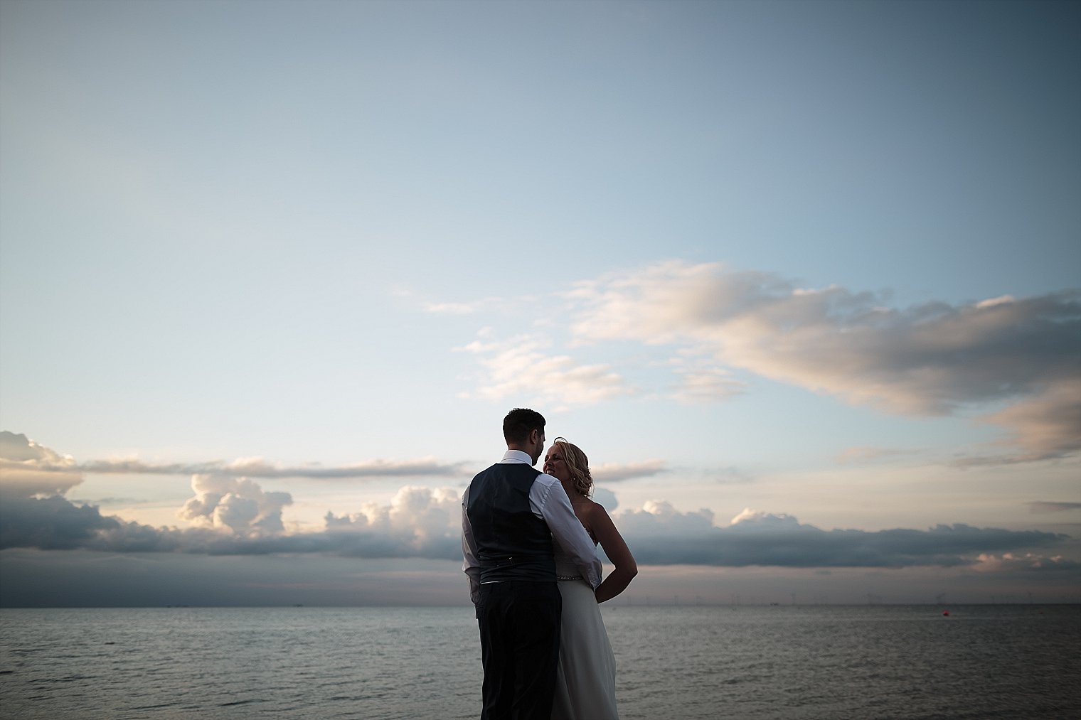Bride and Groom posing against blue sky At East Quay Wedding venue