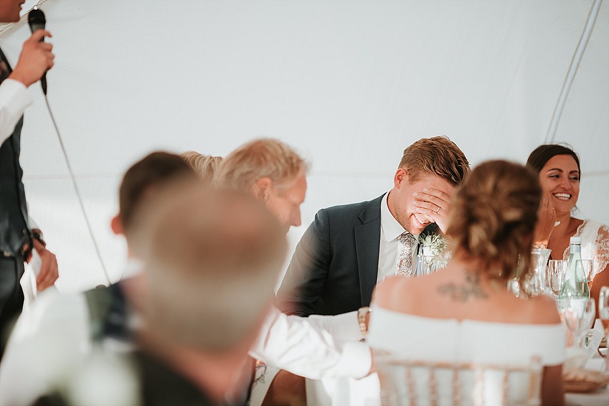 groom with his head in his hands during best mans speech