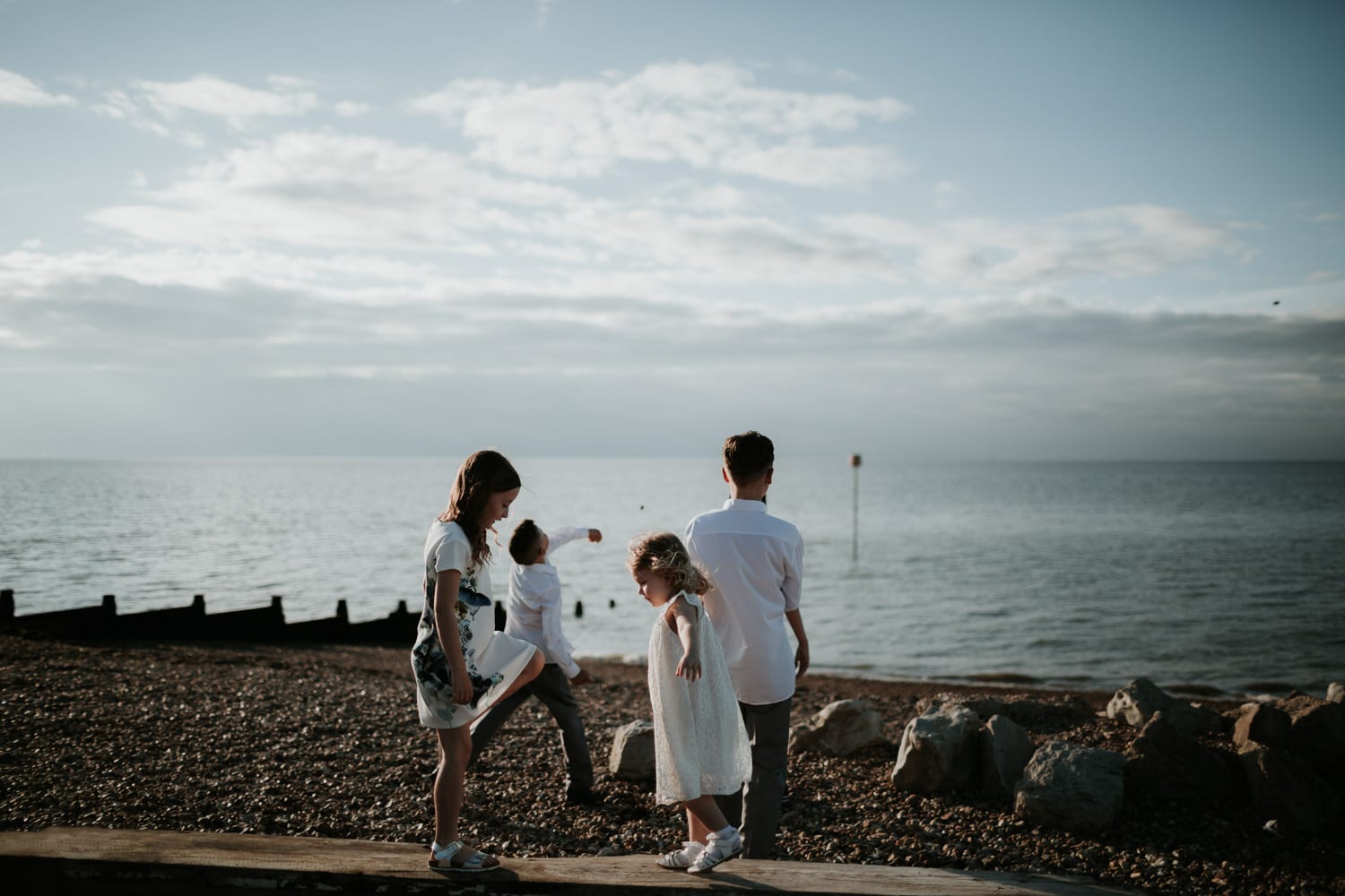 two young girls balancing on log on Whitstable beach
