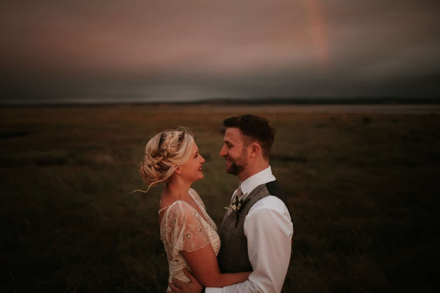 Bride and Groom hugging at sunset against a foreboding orange sky at The Ferry House Inn Kent