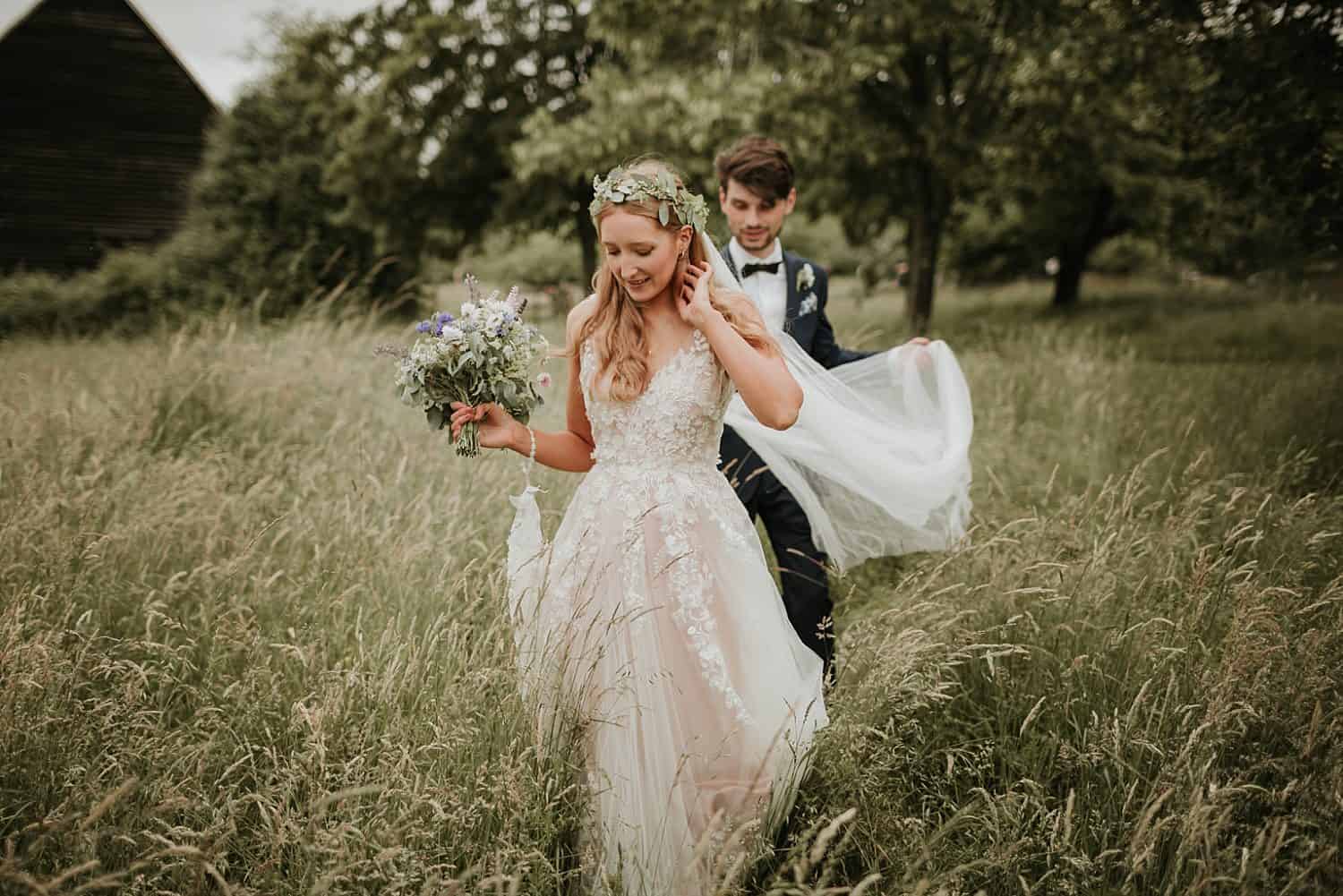 Bride and groom walking through long grass