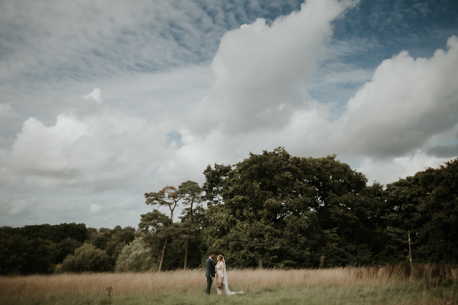 Bride and Groom standing near woodland hand in hand after their wedding service at Oak Tree Barn Weddings