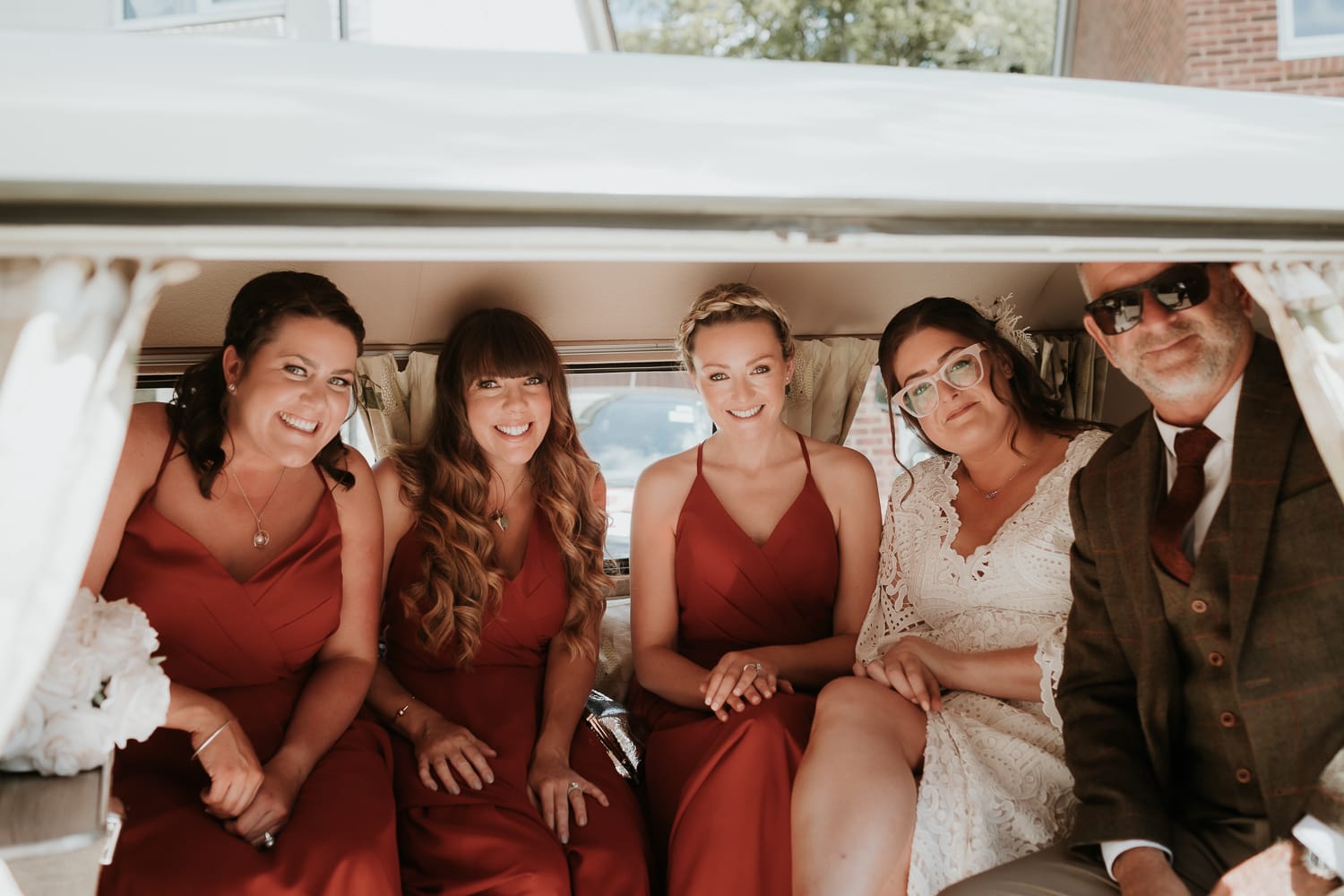 Bride and bridesmaids smiling whilst sat in a campervan
