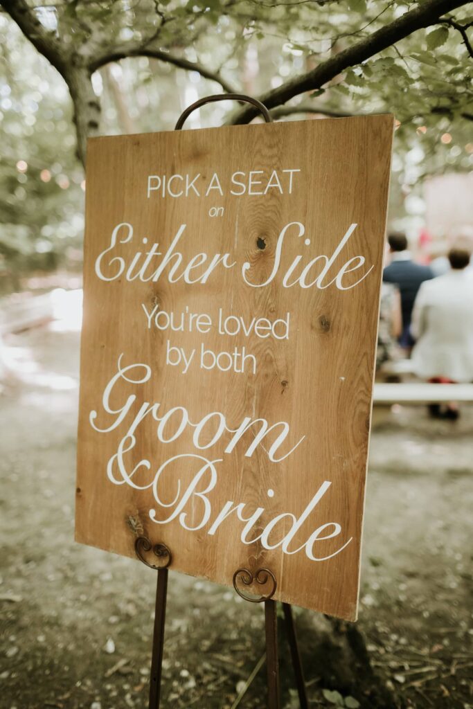 Wedding sign saying pick a seat, either side, you are loved by both groom and bride