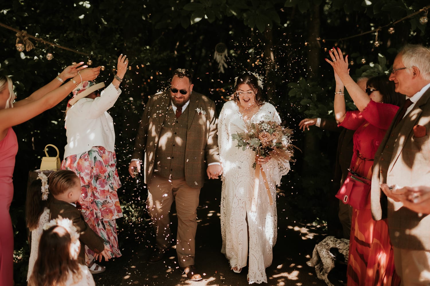 bride and groom smiling and laughing as they walk through confetti at The Dreys