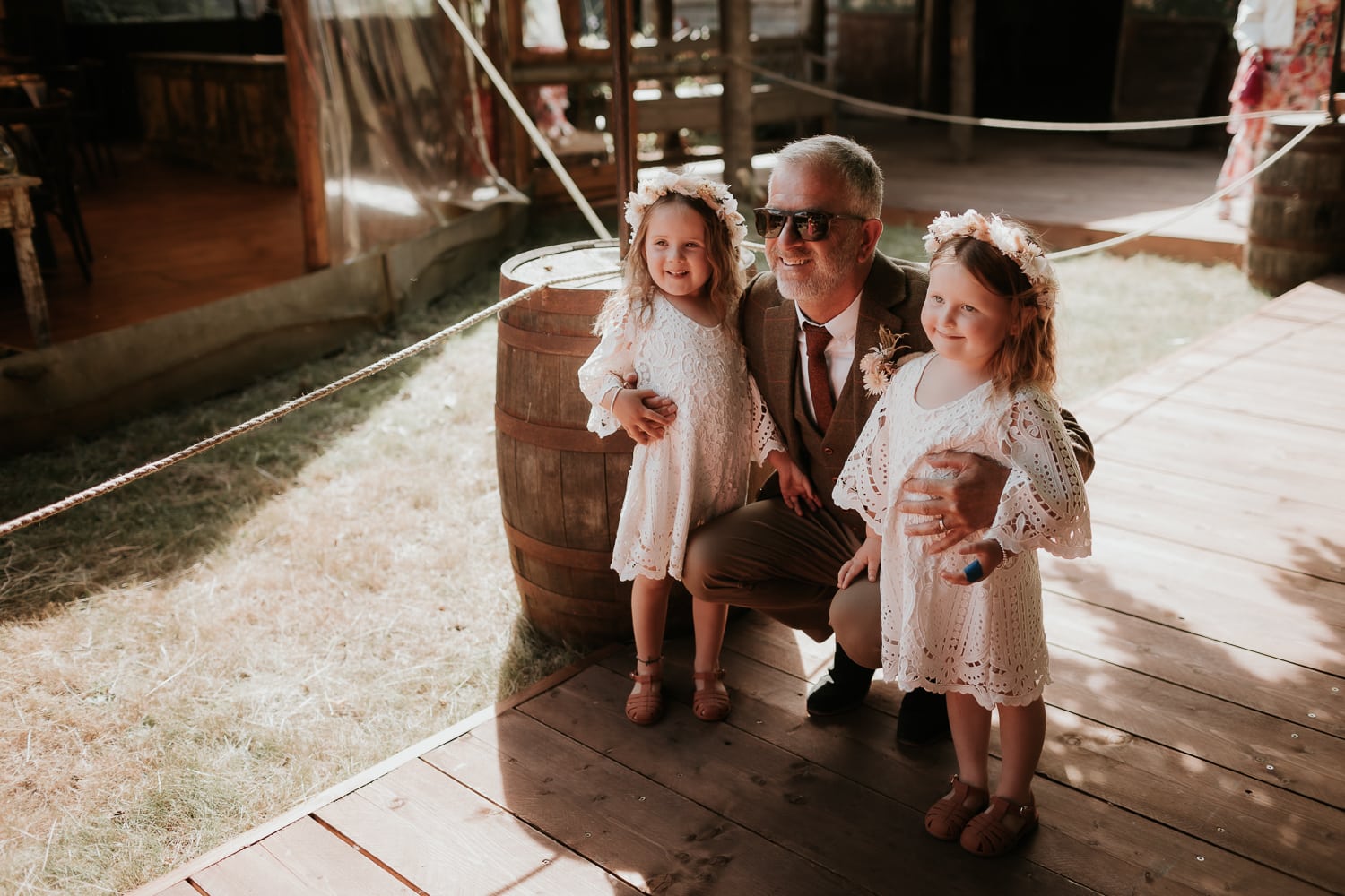 father of the bride posing for a photo with two smiling flower girls