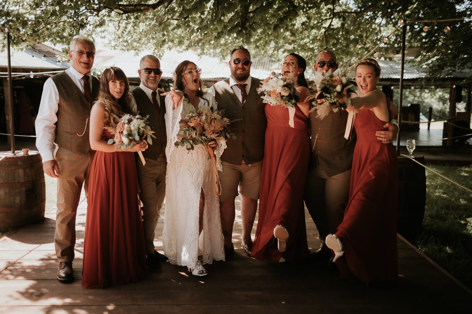 Wedding party joking and laughing whilst posing for a group family photo