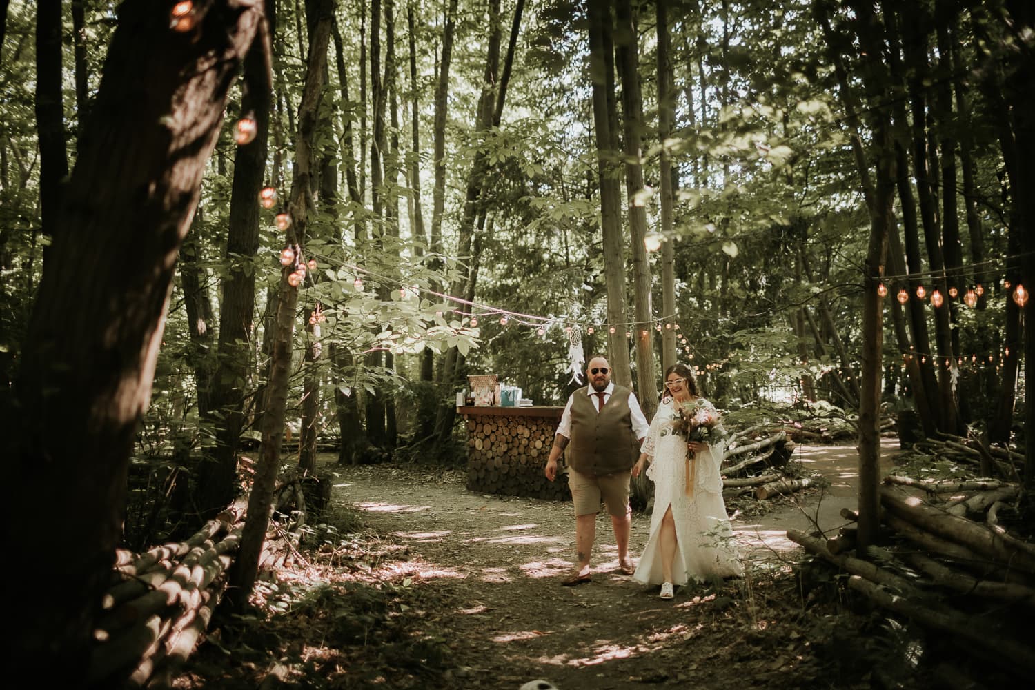 Bride and Groom walking through woodland with her wedding flowers