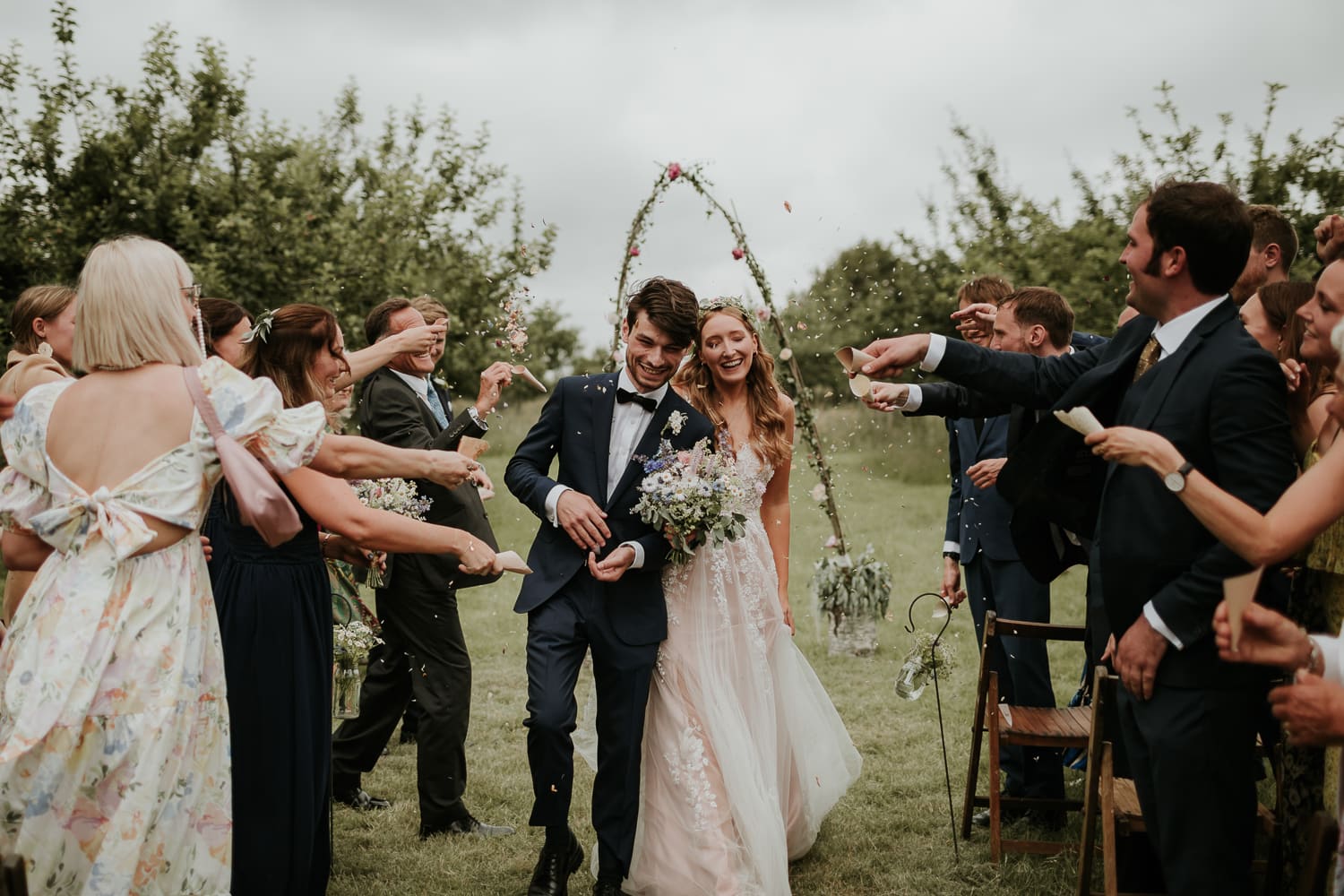 Bride and groom waling down the aisle with confetti