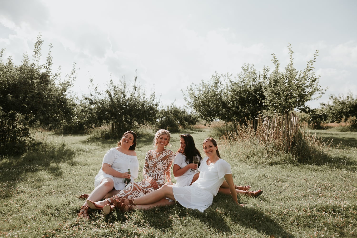 Bride sitting with her bridesmaids with a glass of wine