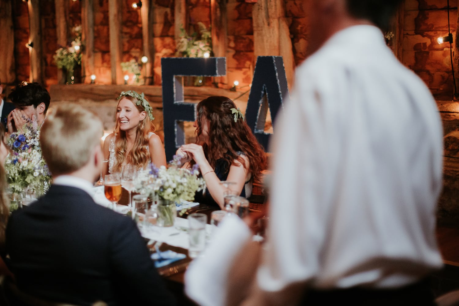 bride laughing whilst her dad gives a speech